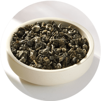 Cup of loose green tea leaves.